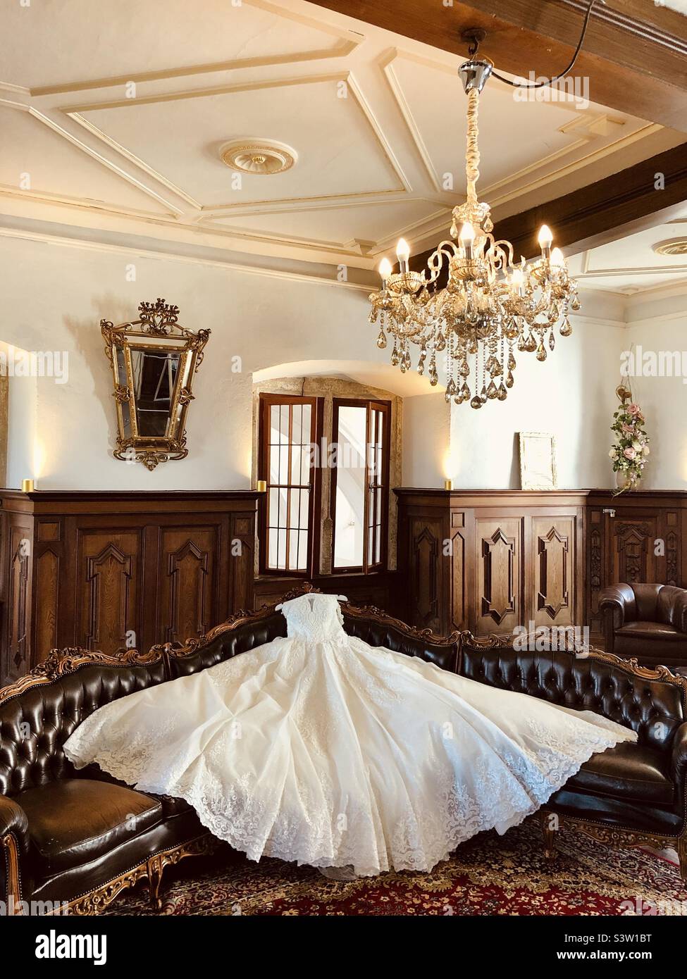 Élégante robe de mariage sur le banc dans une ancienne chambre rétro avec fenêtres en bois Banque D'Images