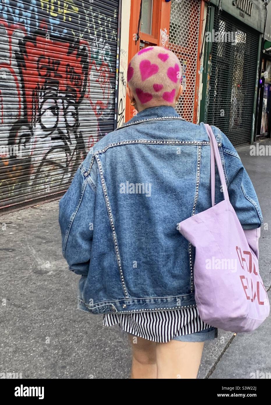 Femme avec coeur rose coiffure design marchant dans la rue Banque D'Images