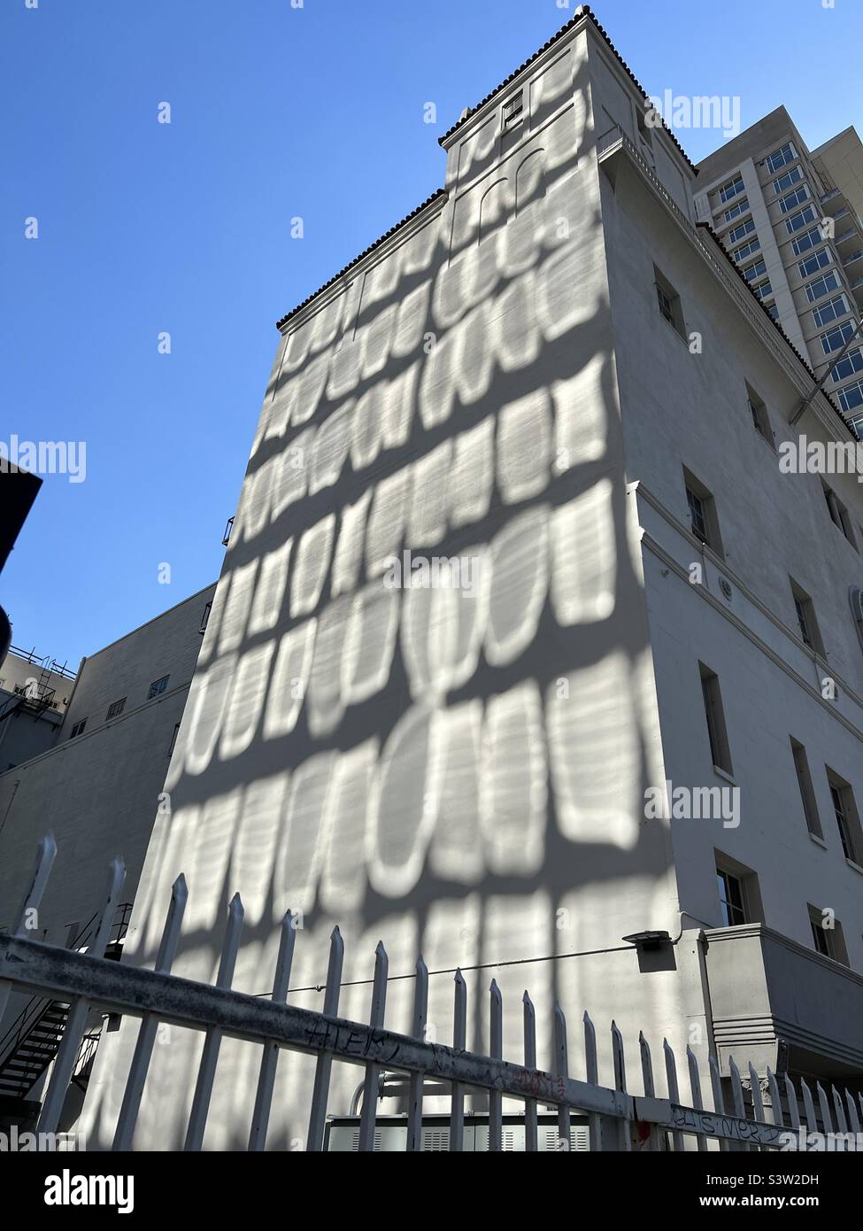LOS ANGELES, CA, MAR 2022 : réflexions de fenêtres d'un bâtiment voisin, créant un motif abstrait sur un mur en béton blanc dans le centre-ville - Image de stock capturée avec un smartphone