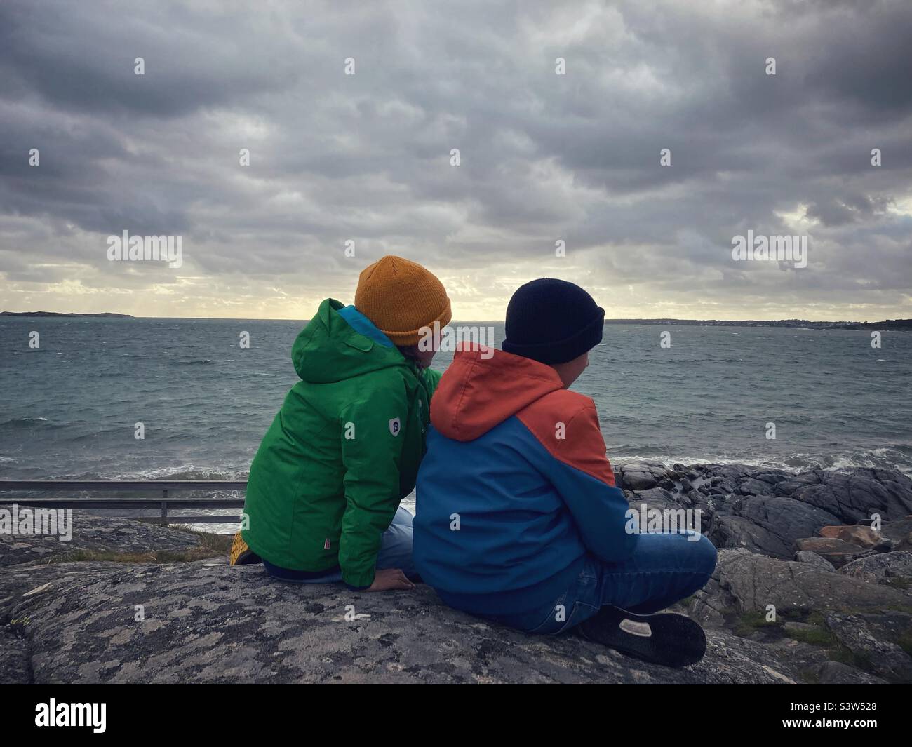 Deux frères ou amis âgés de huit ou neuf ans et onze ou douze ans regardant la mer baltique sur la côte ouest suédoise pendant une tempête Banque D'Images