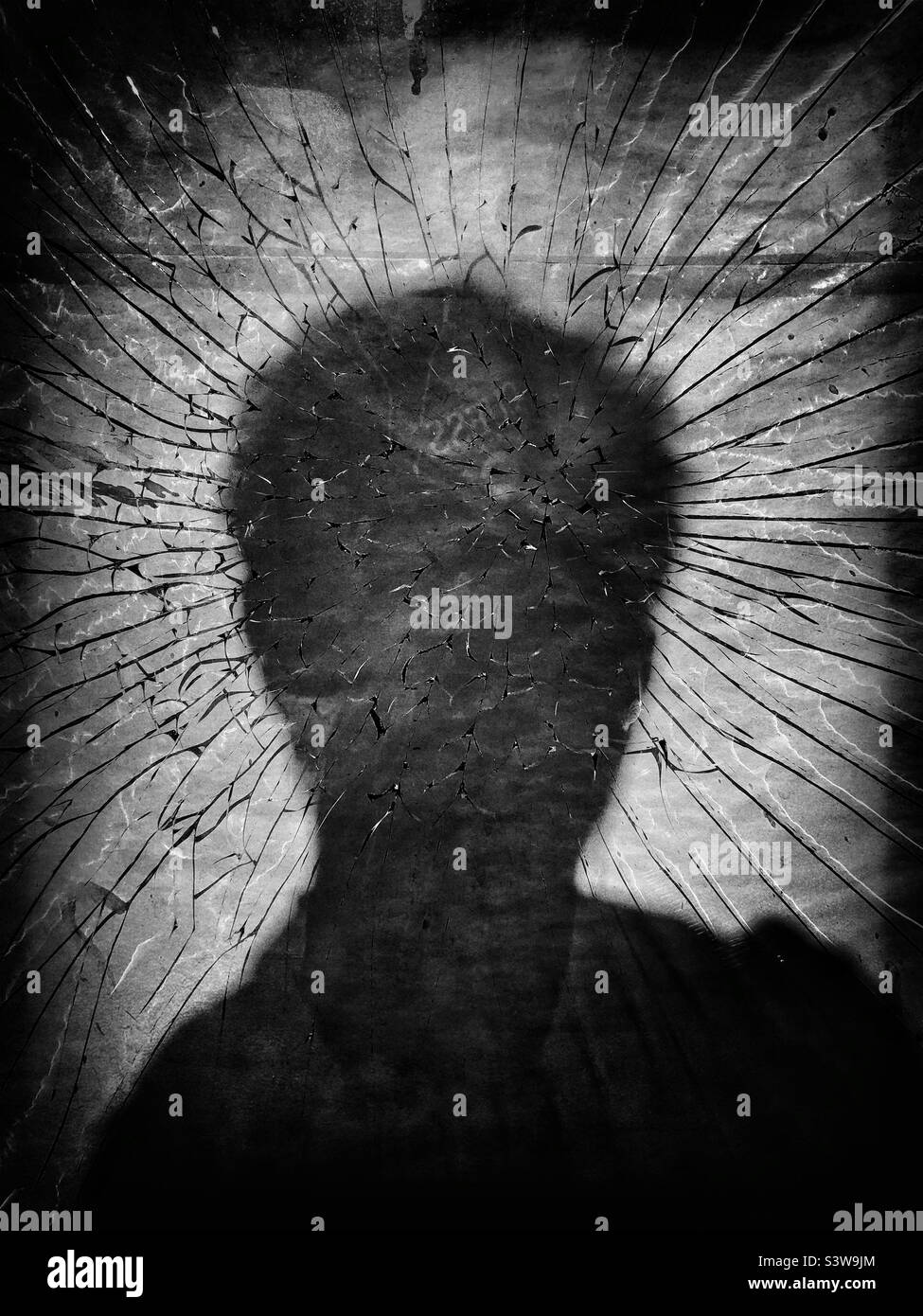 Silhouette d'une personne contre du verre brisé Banque D'Images