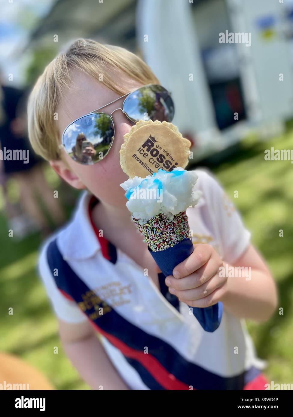 Petit garçon avec des lunettes de soleil et une grande glace Banque D'Images