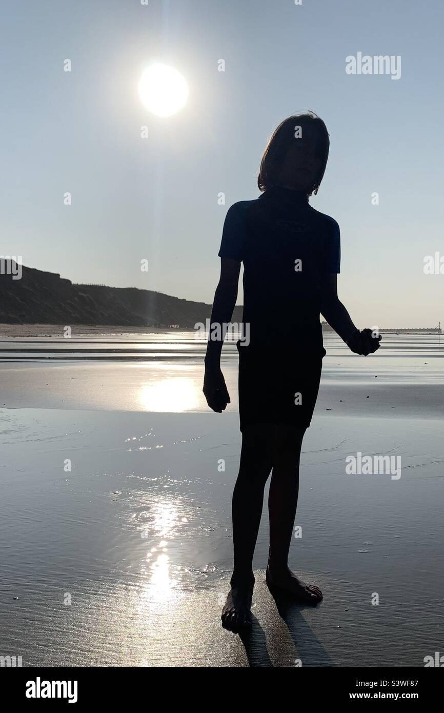 Figure d'un garçon silhoueté par le soleil brillant Banque D'Images