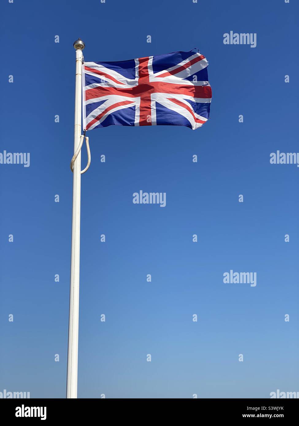 L'Union Jack - drapeau du Royaume-Uni, de la Grande-Bretagne et de l'Irlande du Nord, flotte dans un ciel bleu ensoleillé. Ce drapeau est visible en Angleterre, en Écosse, au pays de Galles et en Nouvelle-Écosse Photo ©️ COLIN HOSKINS. - Image de stock capturée avec un smartphone