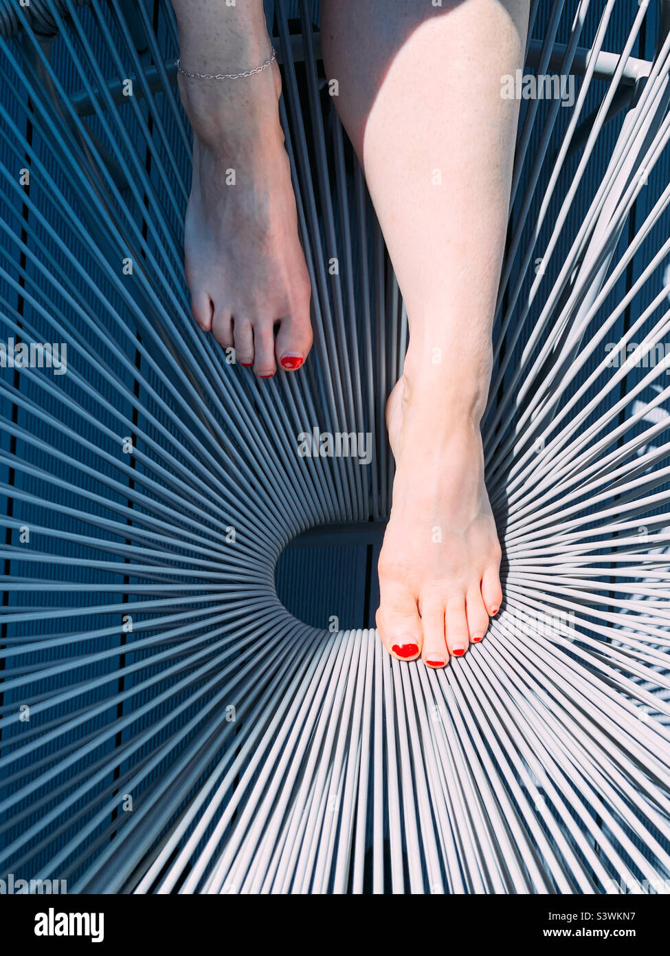 Femme jambes sur une chaise de jardin Banque D'Images