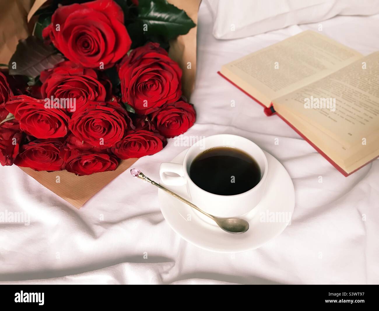 Tasse de café, roses rouges et livre dans le lit blanc - Image de stock capturée avec un smartphone