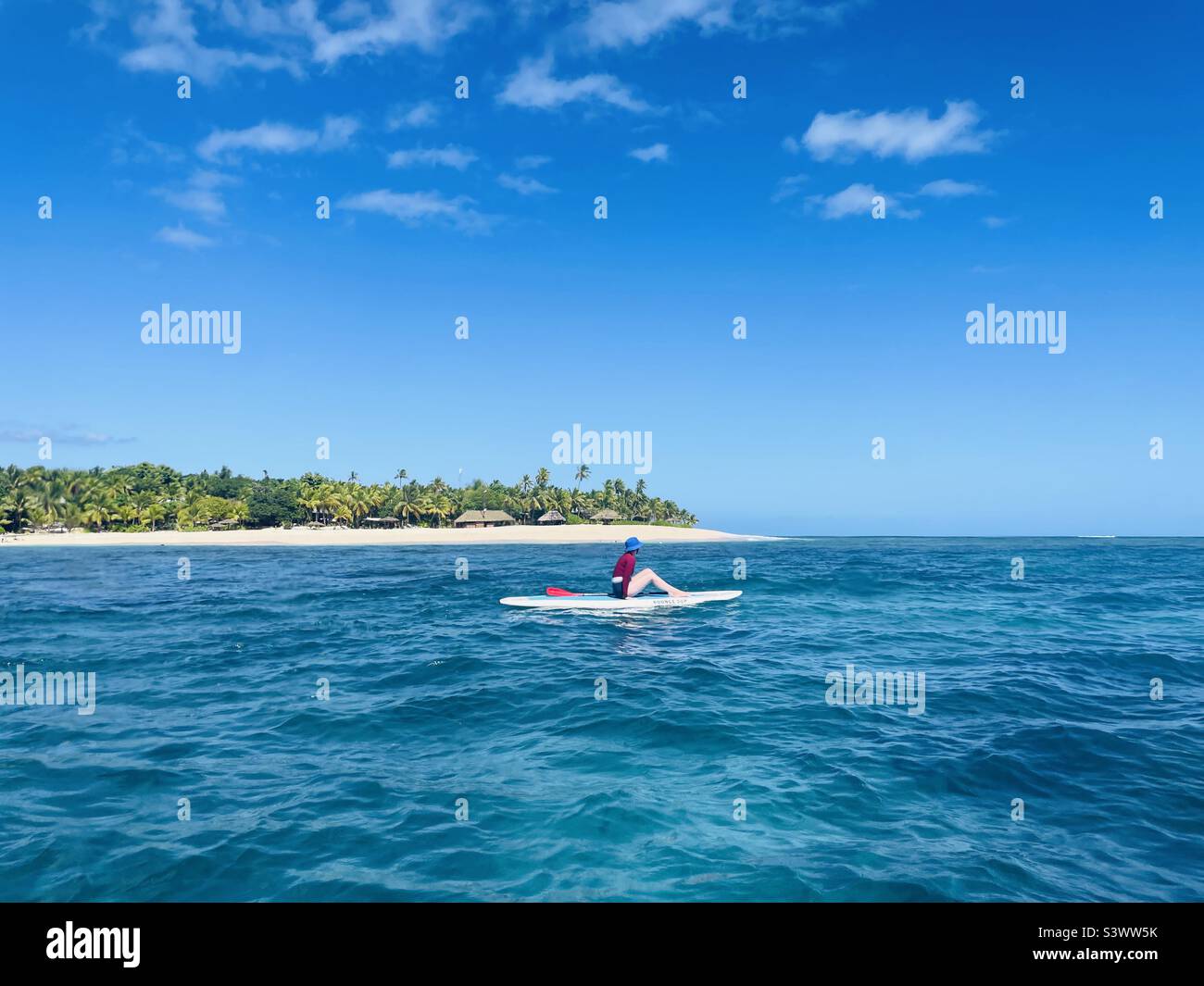 Une femme assise pendant le paddle-board. Île de Tavarua, Fidji. - Image de stock capturée avec un smartphone Une femme assise pendant le paddle-board. Île de Tavarua, Fidji. - Image de stock capturée avec un smartphone