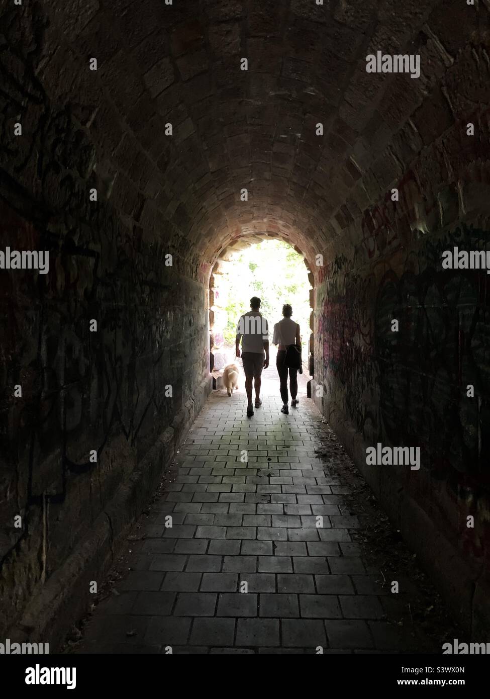 Couple marchant dans le tunnel avec un chien Banque D'Images