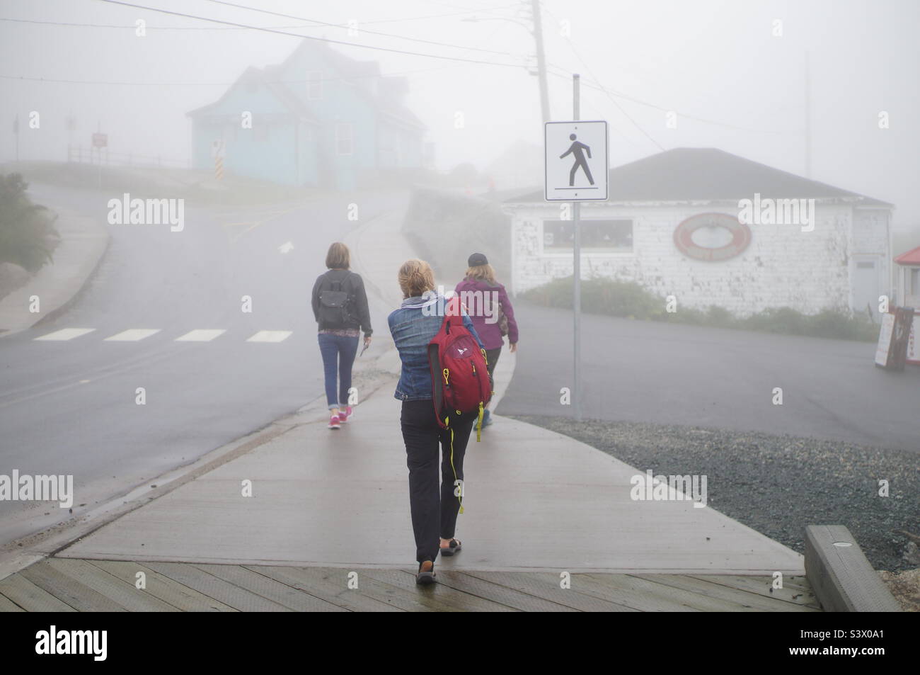 Trois amis qui marchent dans le brouillard épais de Peggy’s Cove. Banque D'Images