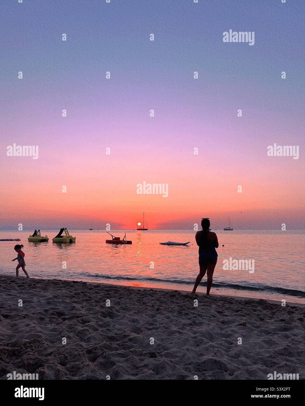 Une mère et un enfant regardent le coucher du soleil sur la plage de Cefalù, en Sicile, en Italie Banque D'Images