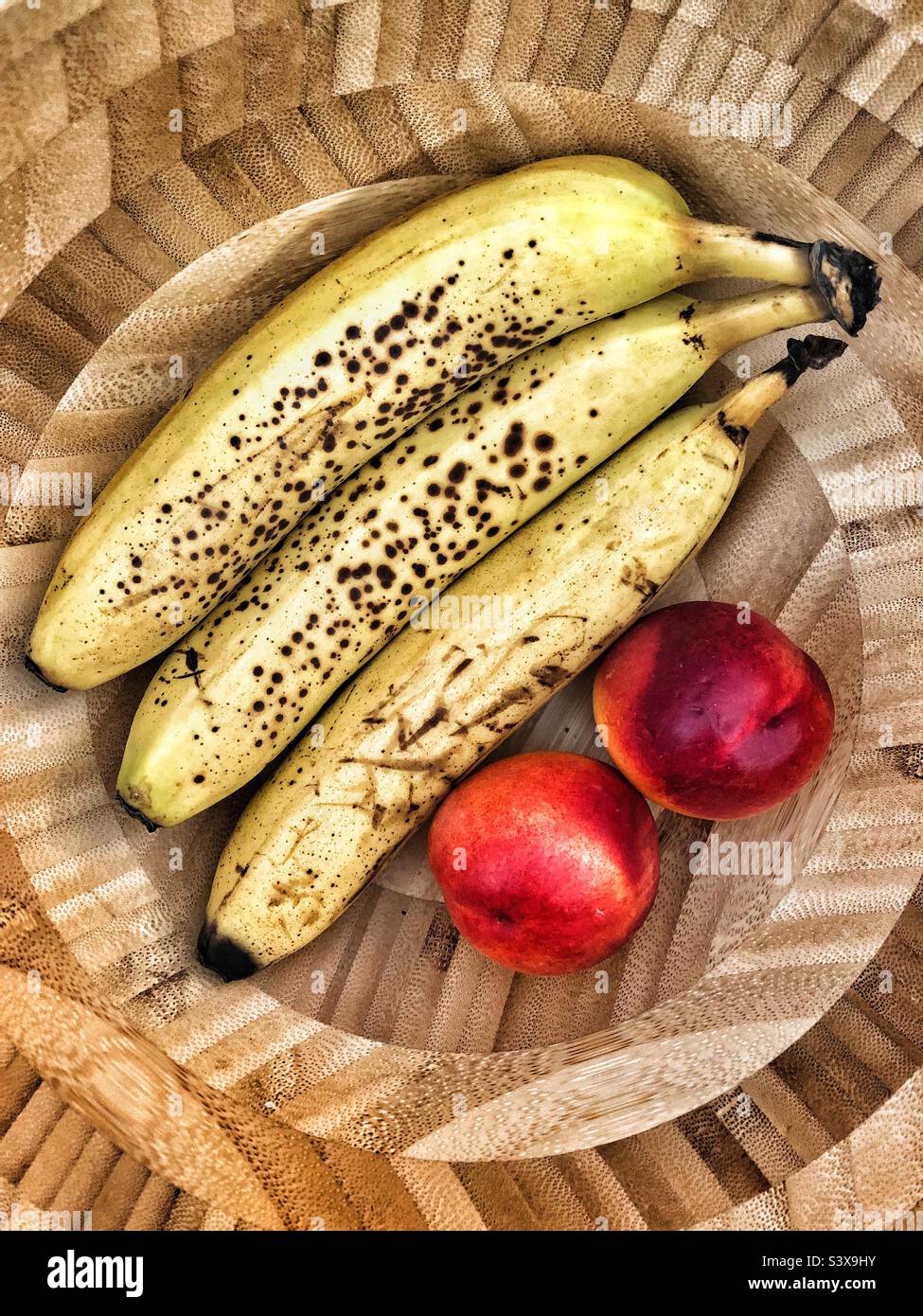 Bananes mûres et nectarines dans un bol de fruits Banque D'Images