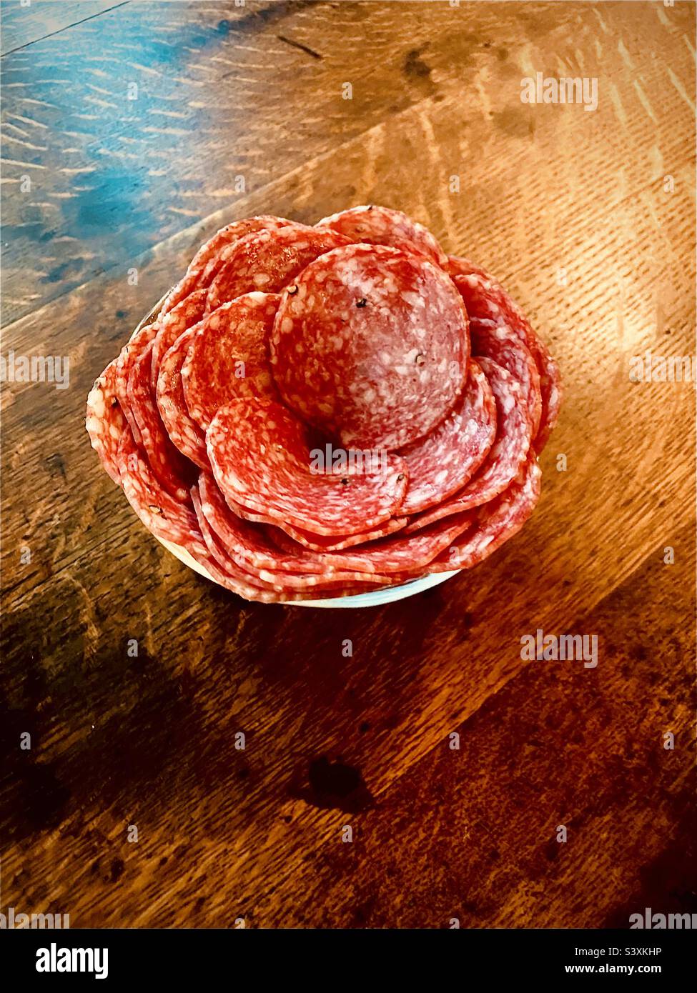 Salami, bol de salami en forme de rose, sur une table en bois Banque D'Images