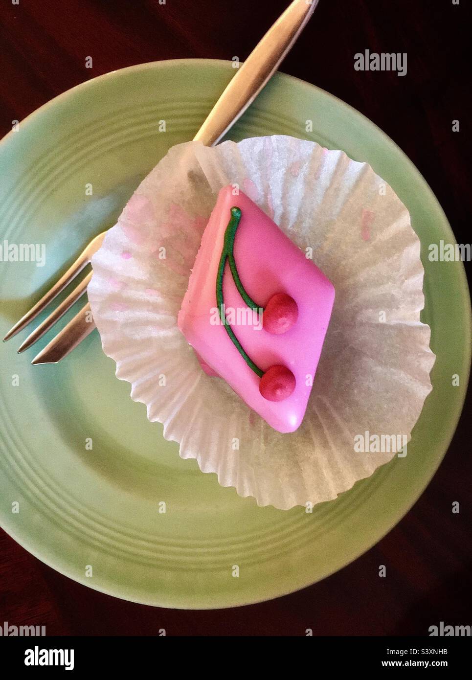 Gâteau au temps de la thé ; joli gâteau rose glacé en forme de losange avec décoration aux cerises Banque D'Images