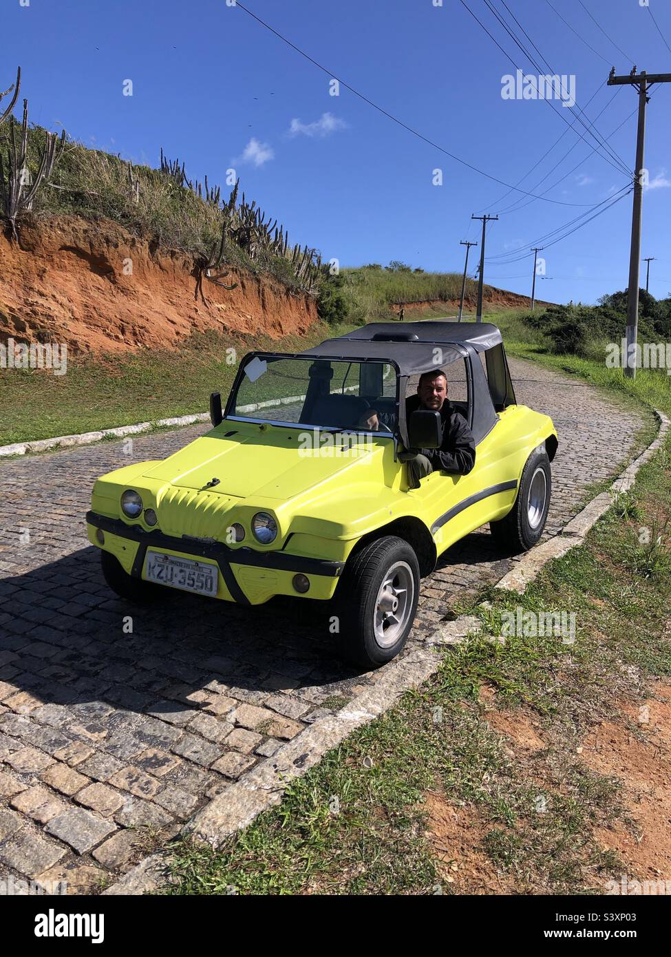 Un homme qui conduit un buggy jaune vif. Banque D'Images