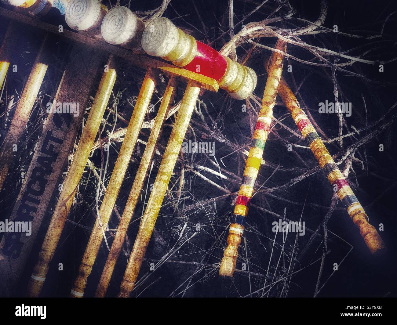 Un vieux jeu de croquet incomplet et cassé, vu jeté dans un champ de mauvaises herbes. Pourtant, les couleurs, les formes et les textures, avec un effet grunge ajouté, font un abstrait intéressant. Banque D'Images