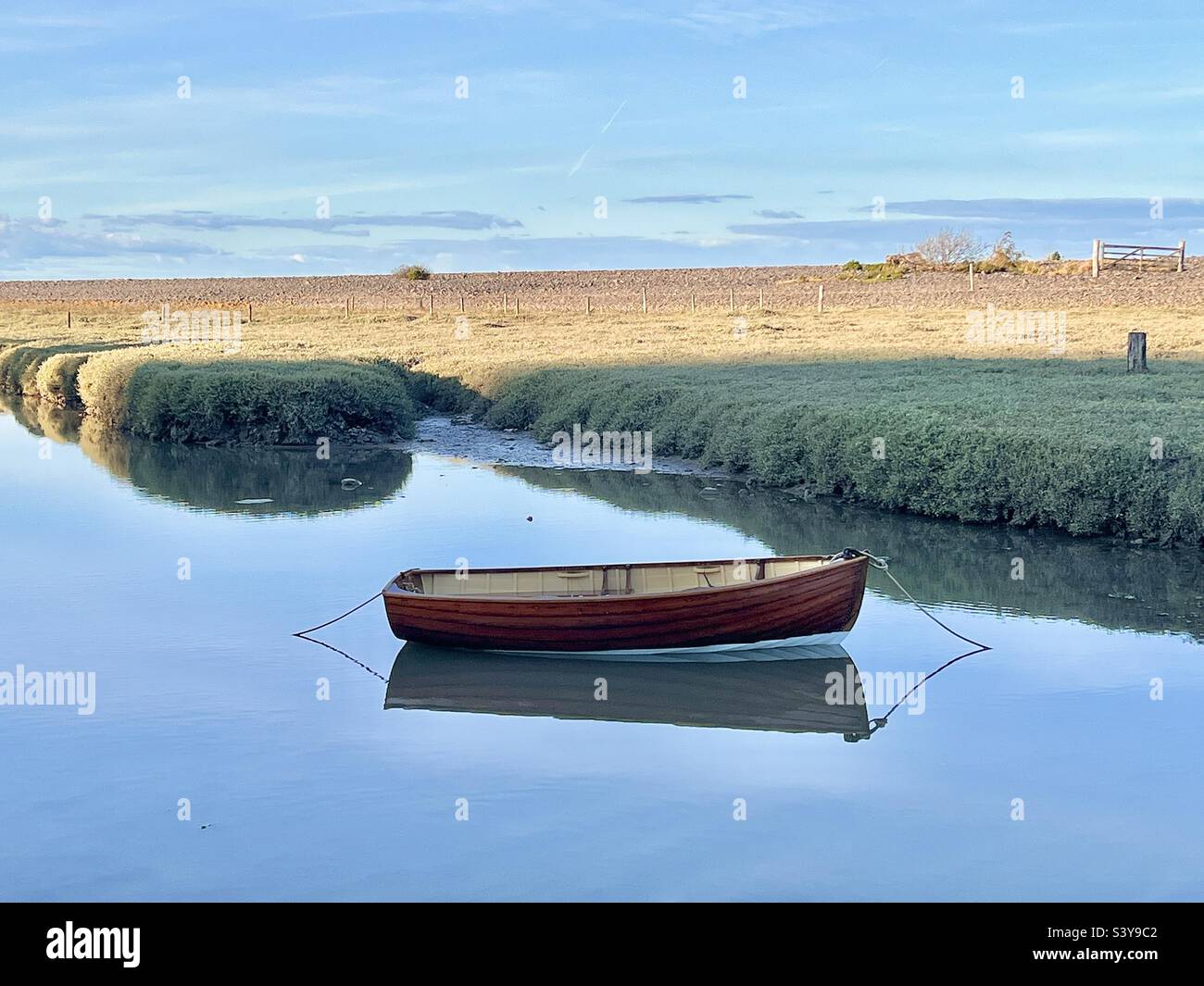 Un petit bateau solitaire flotte sur un miroir encore calme comme l'eau près du weir de Porlock Somerset en automne Banque D'Images