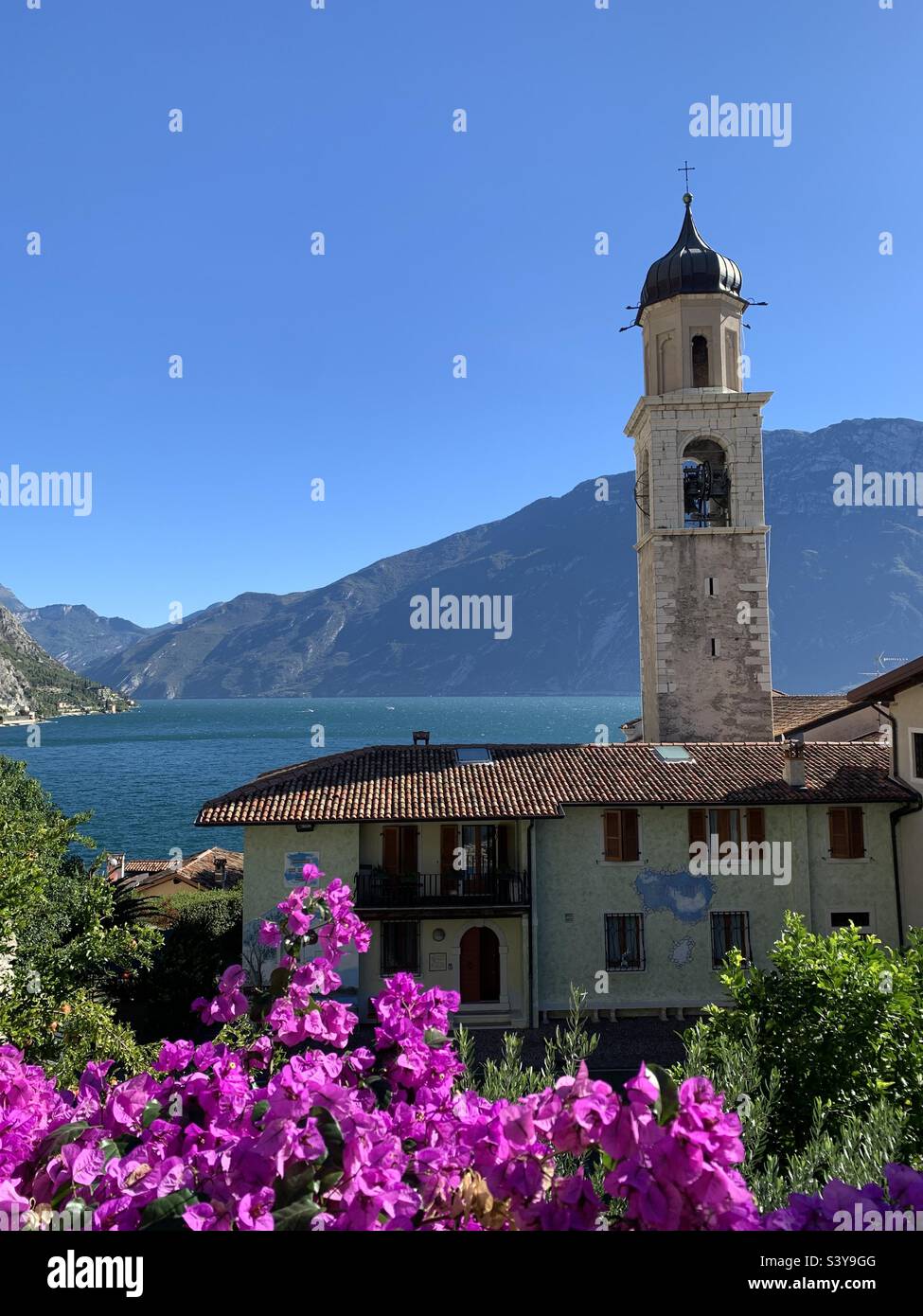 Église et fleurs roses au lac de Garde de Limone par une journée d'été avec ciel bleu - Image de stock capturée avec un smartphone