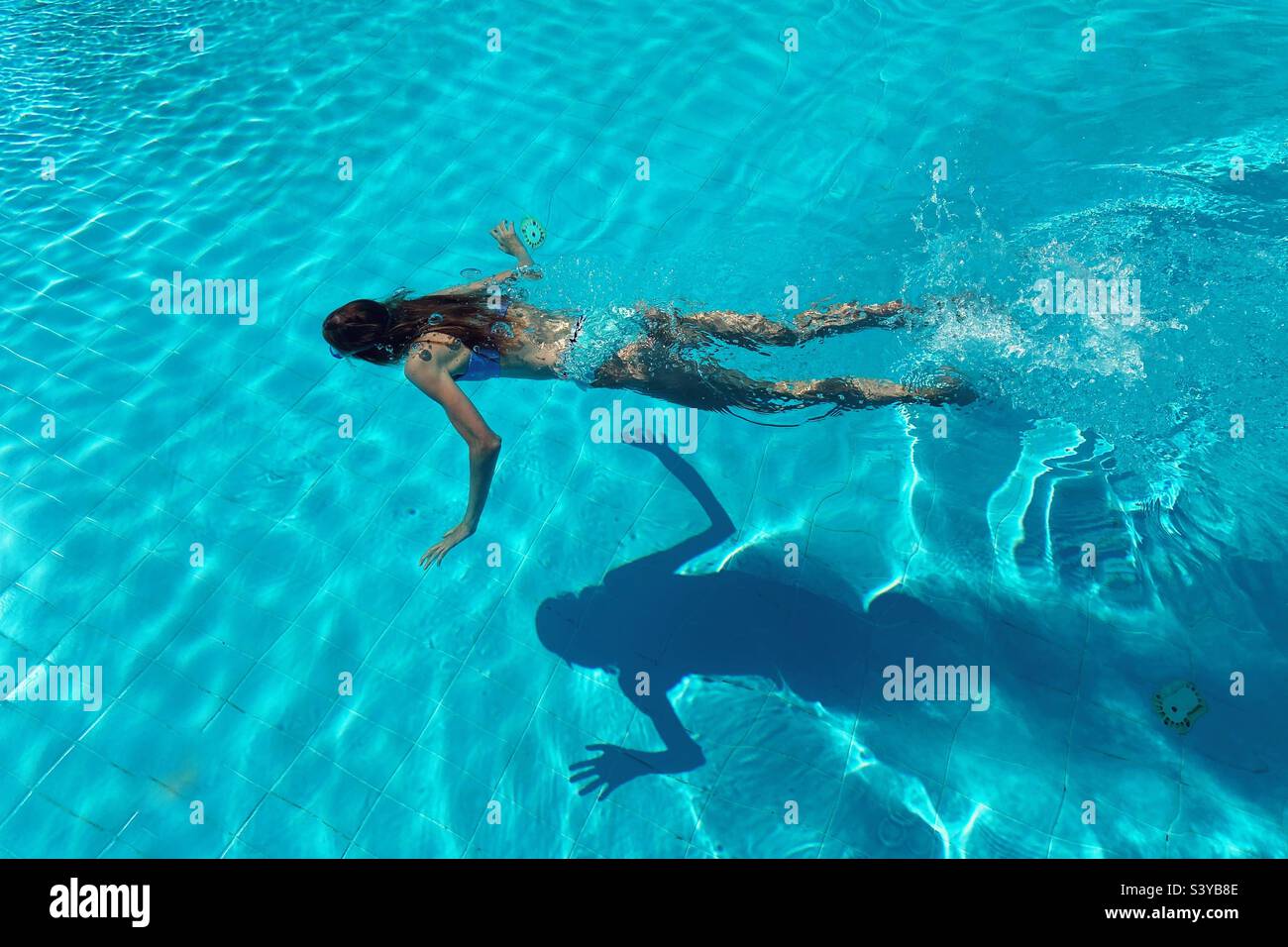 Fille nageant l'ombre de coulée sur le fond de la piscine Banque D'Images