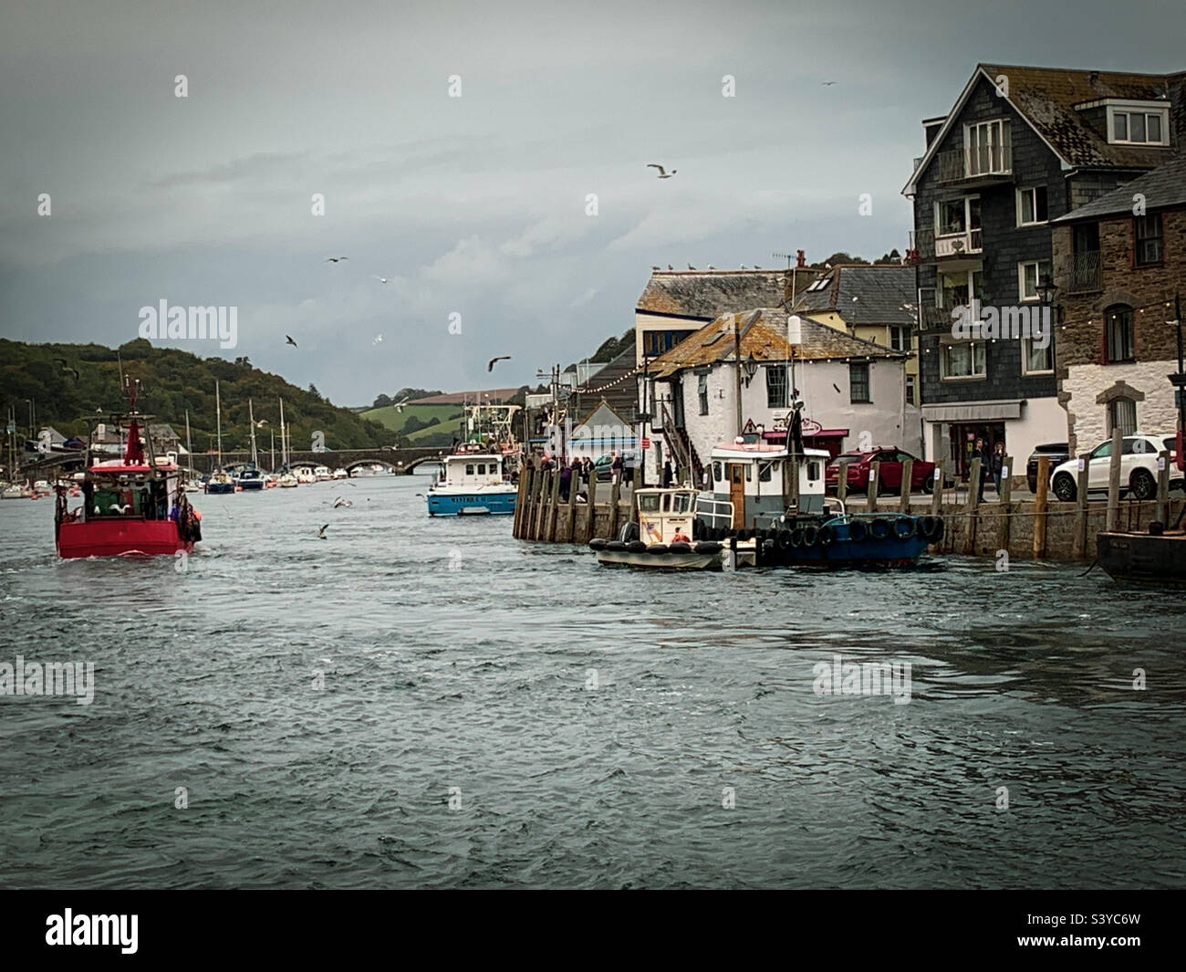 Un bateau de pêche de retour mène le long de la rivière jusqu'au quai du port de Looe, à Cornwall, au Royaume-Uni - Image de stock capturée avec un smartphone