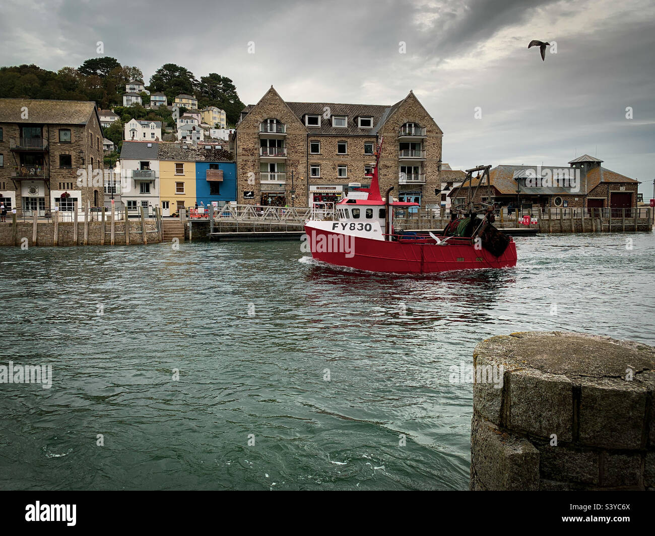 Un bateau de pêche de retour mène le long de la rivière jusqu'au quai du port de Looe, à Cornwall, au Royaume-Uni - Image de stock capturée avec un smartphone