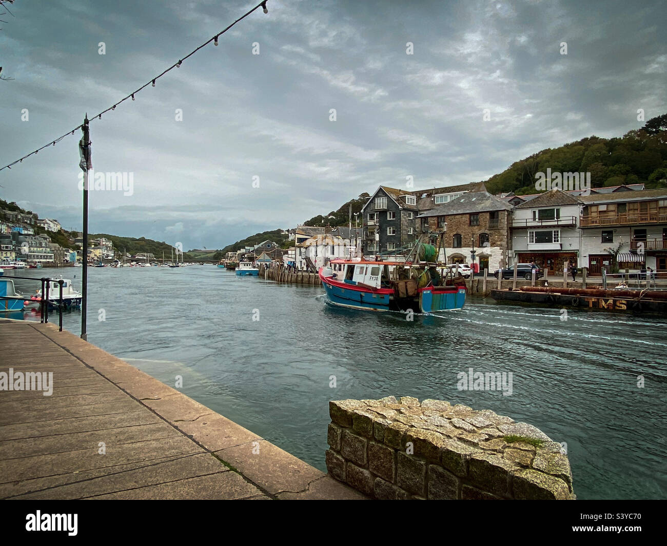 Un bateau de pêche de retour mène le long de la rivière jusqu'au quai du port de Looe, à Cornwall, au Royaume-Uni - Image de stock capturée avec un smartphone