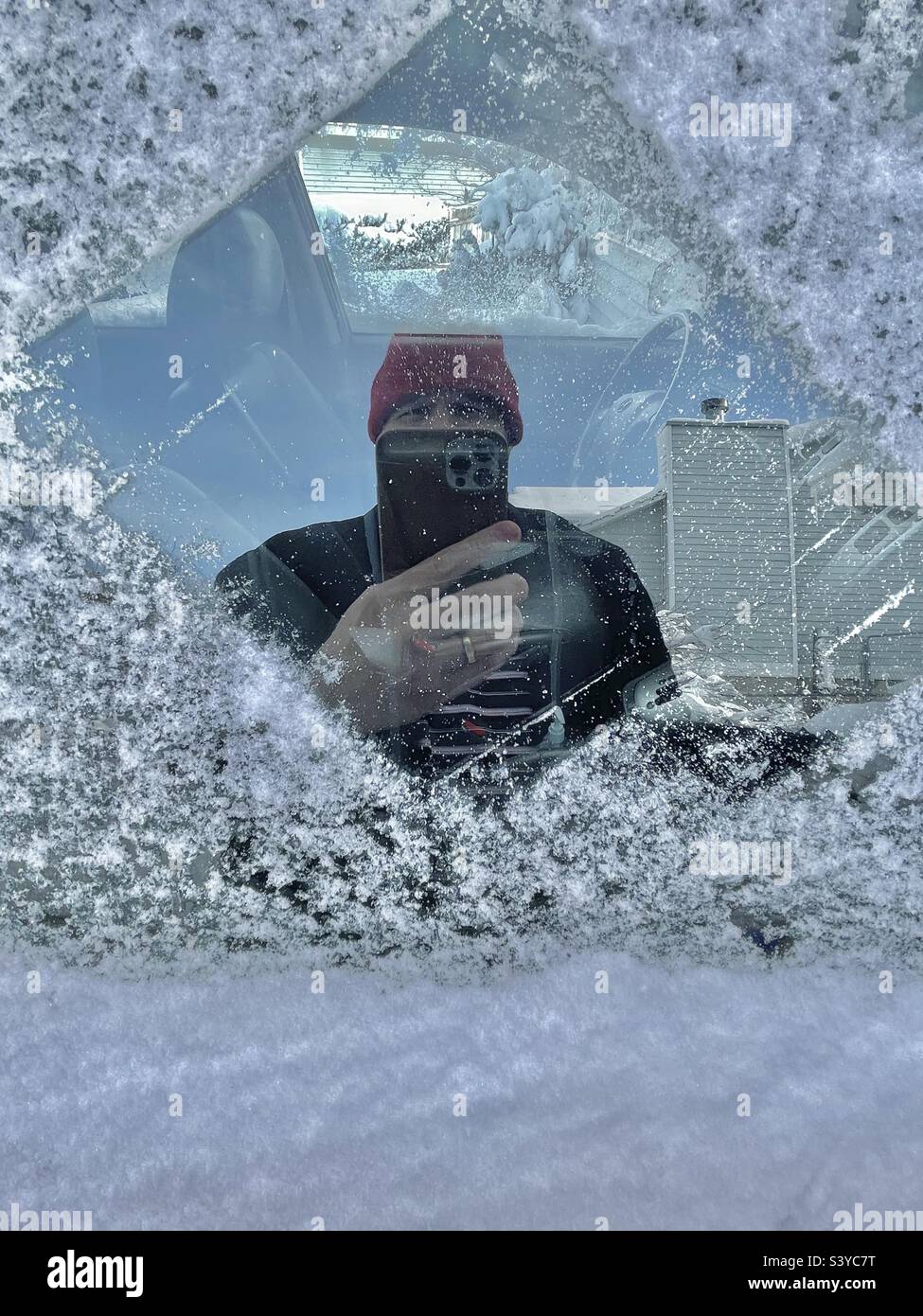 De la neige fraîche et de la glace ont été raclées par une fenêtre côté passager après une forte chute de neige qui a eu lieu la nuit dans ce quartier de l'Utah, aux États-Unis, ce qui a entraîné un selfie involontaire dans le reflet de la vitre. Banque D'Images