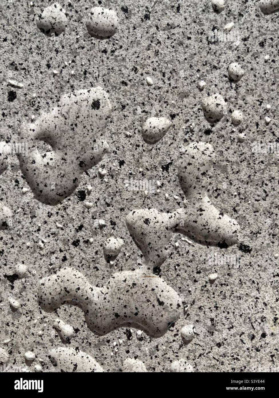 L'eau tombe sur une surface grise avec des points noirs mouchetés - Image de stock capturée avec un smartphone