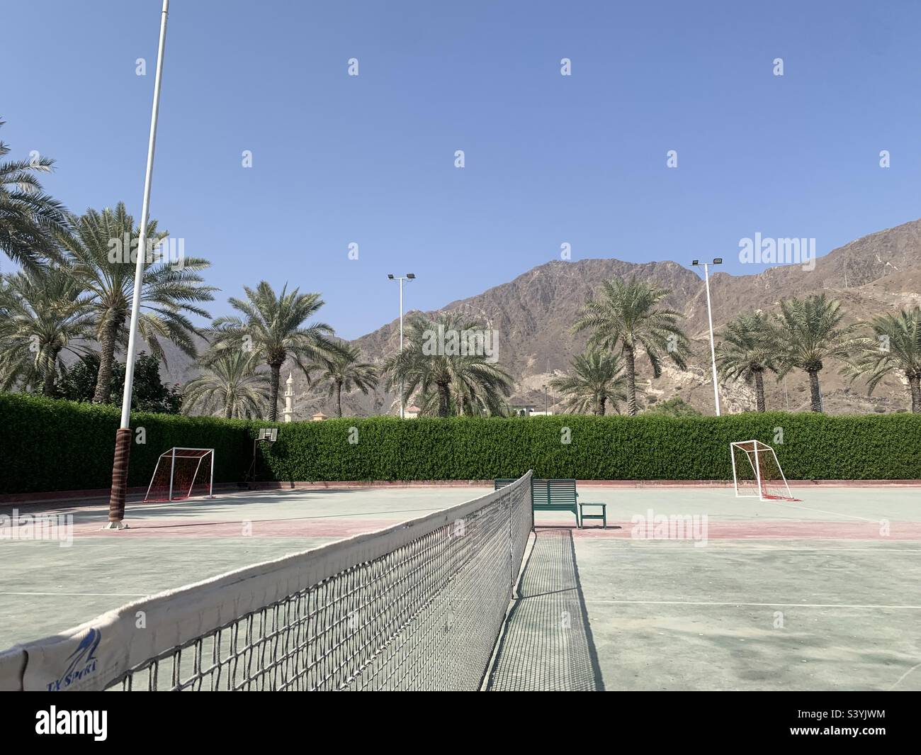 Court de tennis poussiéreux avec vue sur les montagnes de Hajar à Fujairah, eau Banque D'Images