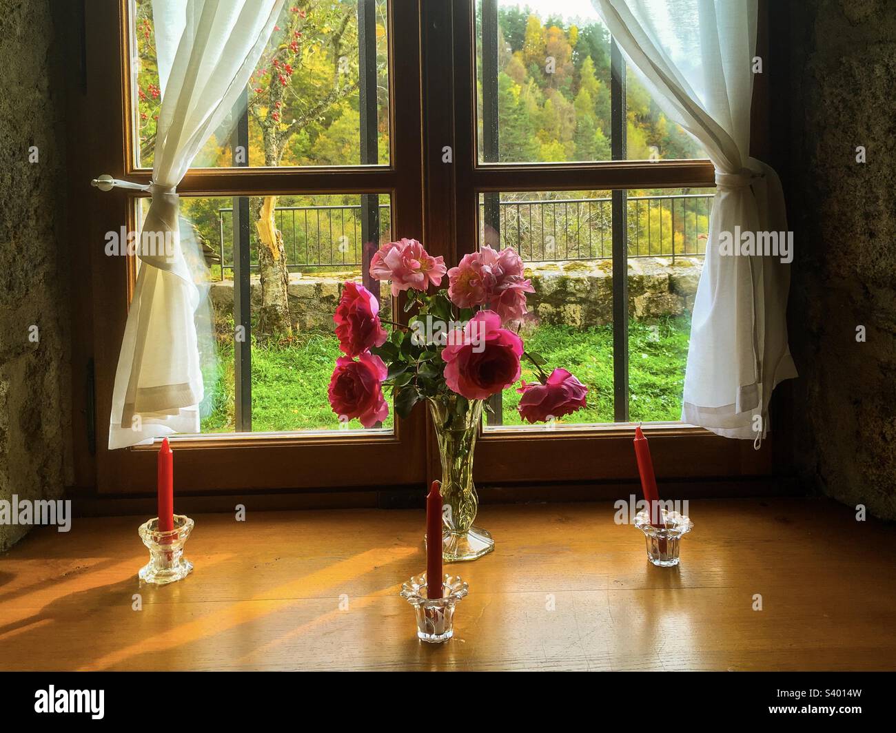 Vase de belles roses rouges sur le rebord d'une vieille maison en pierre, Lozère, France. Banque D'Images