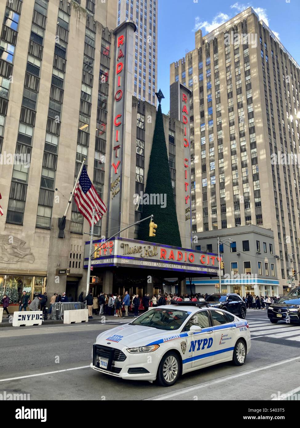 New York, New York, Etats-Unis – 26 novembre 2022: Radio City Music Hall avec arbre de Noël au sommet du chapiteau. Voiture de police de New York (NYPD) devant la photo. - Image de stock capturée avec un smartphone