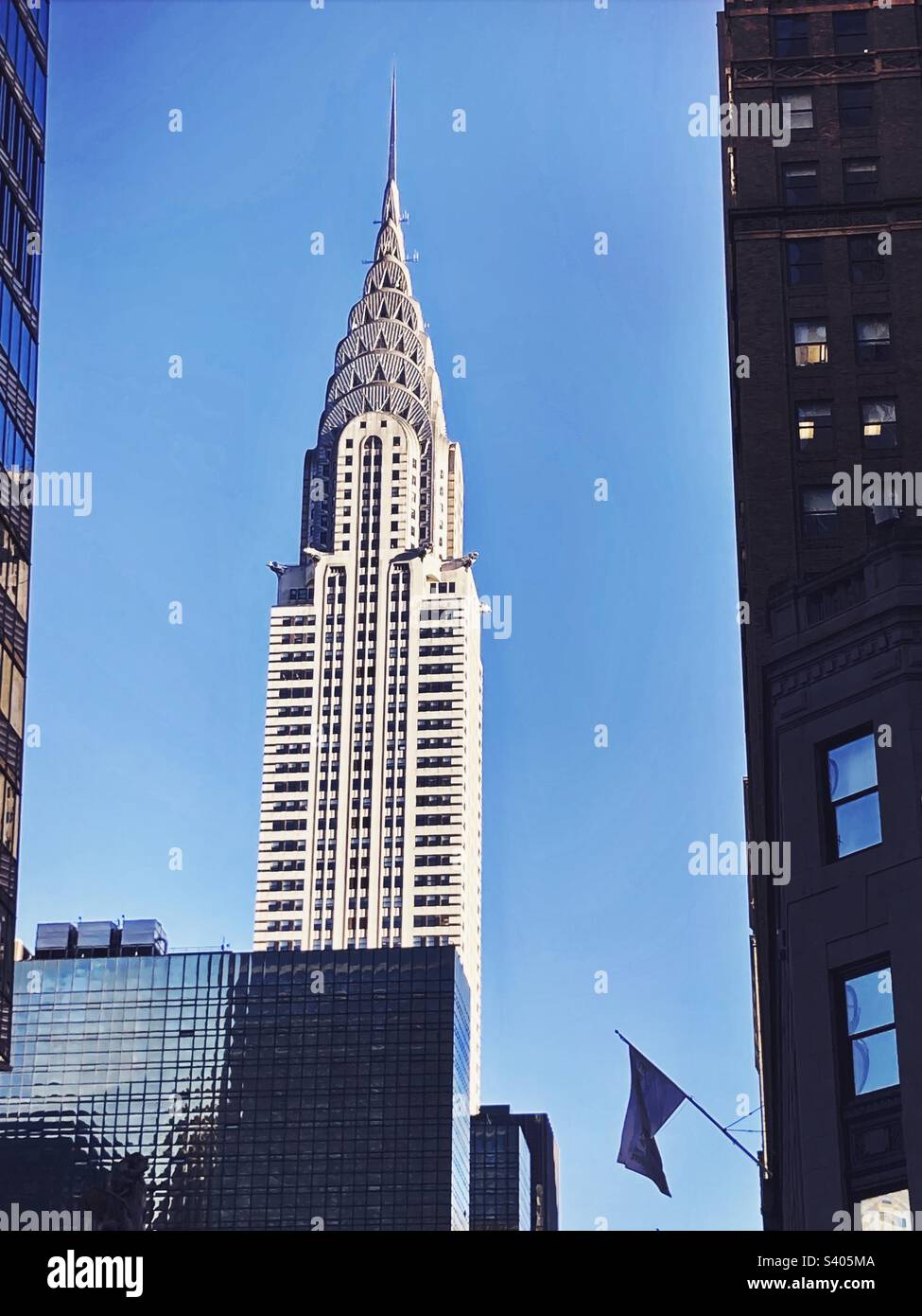 Bâtiment Chrysler dans le centre-ville de Manhattan, New York, encadré par d'autres bâtiments. Ciel bleu derrière. - Image de stock capturée avec un smartphone