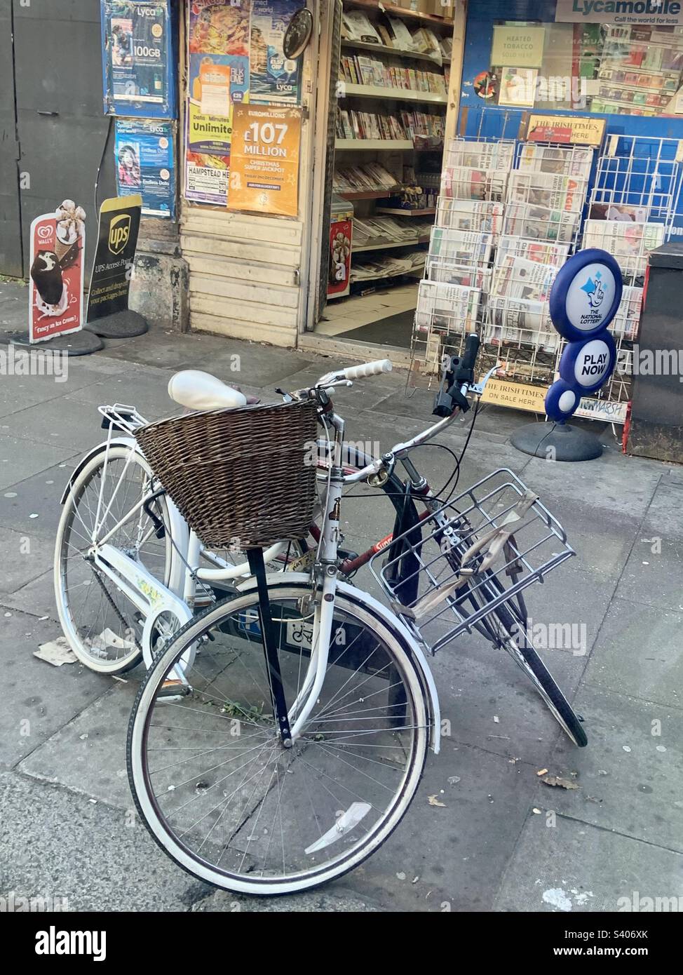 Deux vélos verrouillés en toute sécurité au poste métallique devant une boutique de l'agence de presse à Londres Banque D'Images