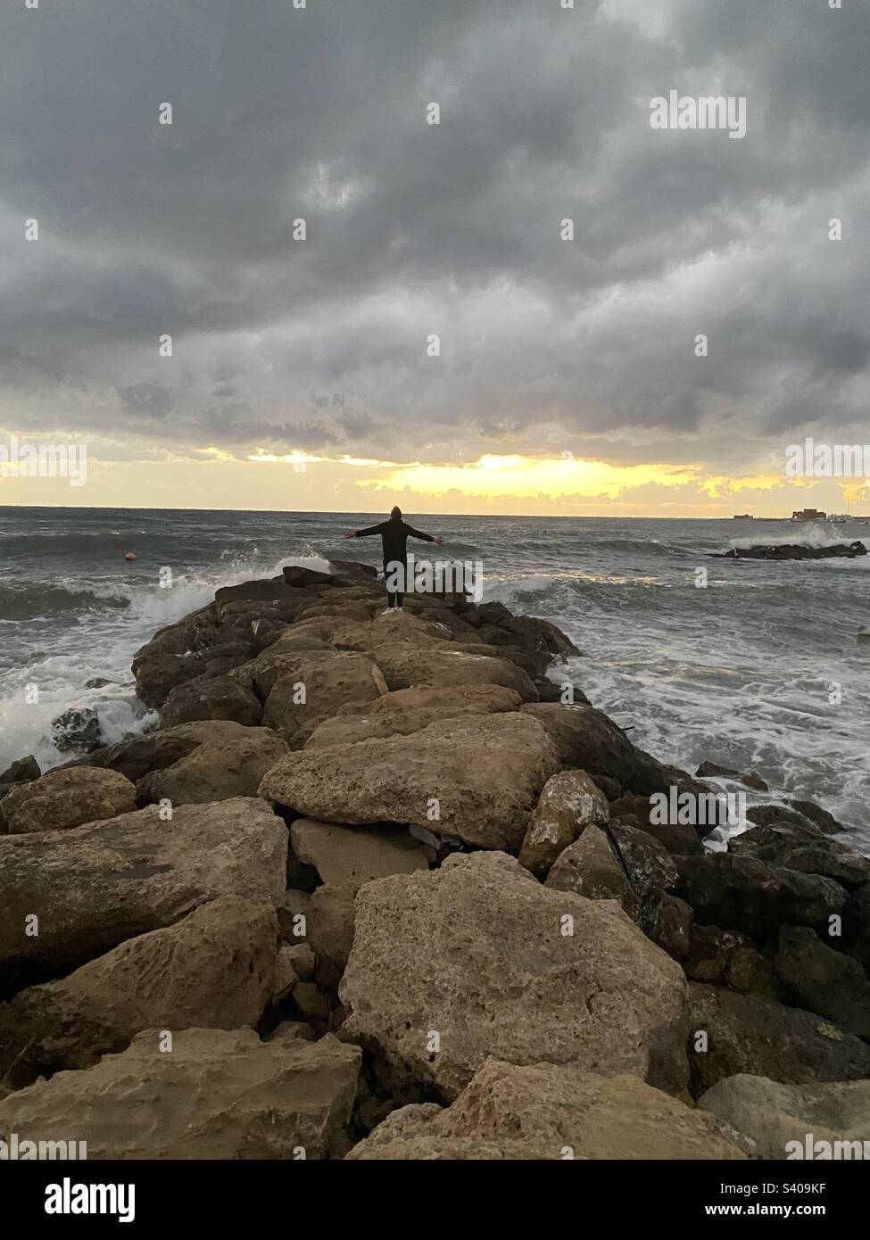 Un homme sur le bord du brise-lames avant la tempête avec ses mains à part Banque D'Images