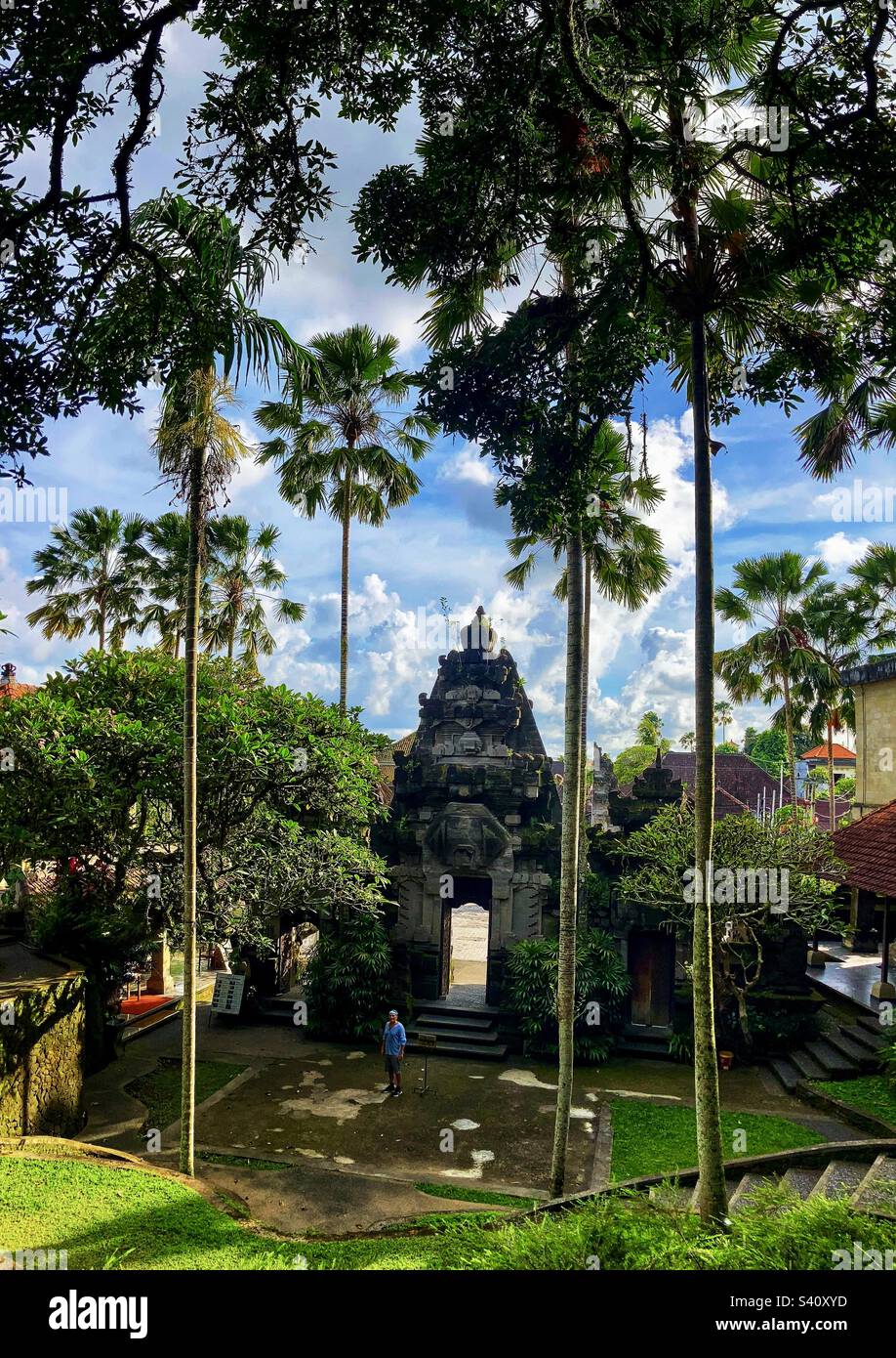 Entrée dans le jardin à Ubud Bali avec homme debout près de la porte avec de grands palmiers Banque D'Images