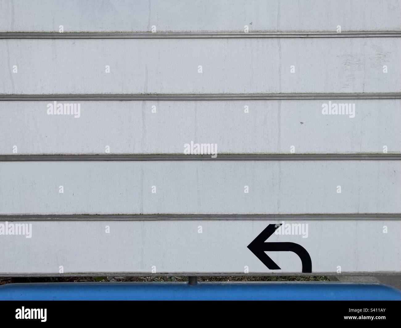 une flèche noire pointe vers la gauche sur un mur segmenté blanc Banque D'Images