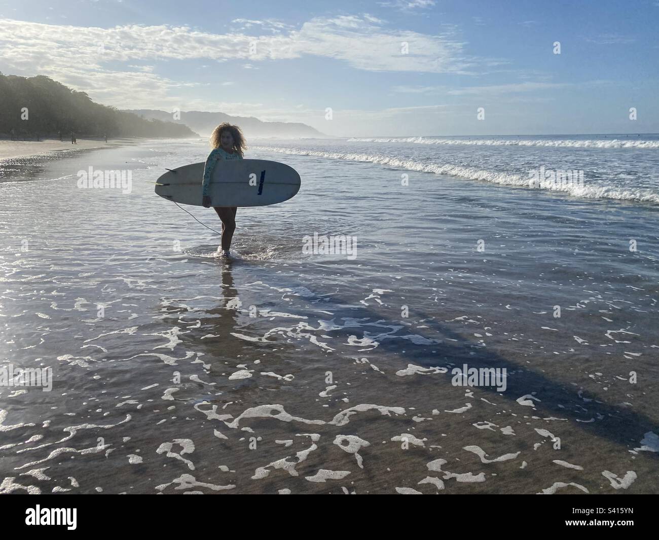 Une femme avec une planche de surf se prépare à aller surfer dans l'océan à Santa Teressa au Costa Rica - Image de stock capturée avec un smartphone