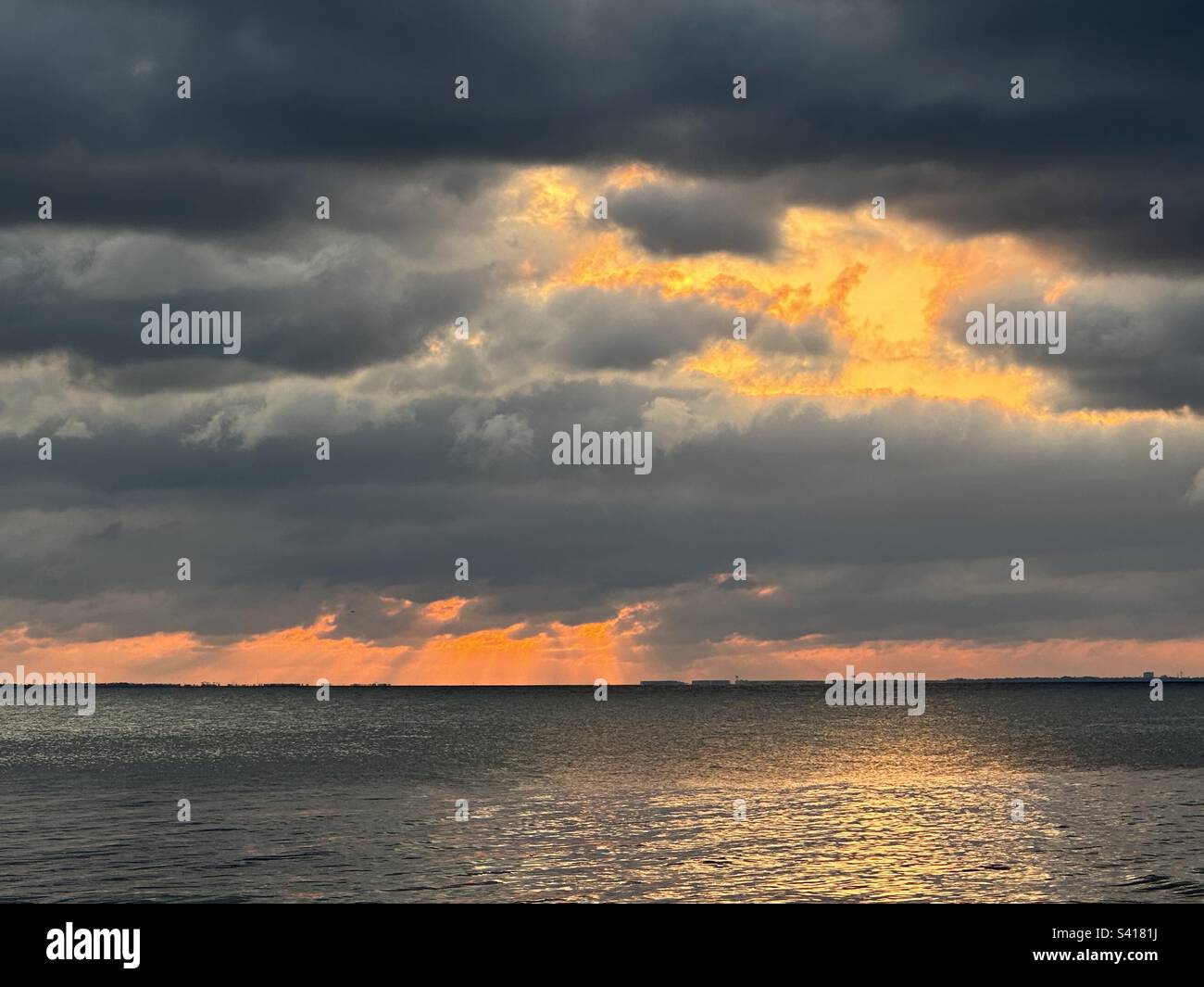 Super nuages au coucher du soleil, le soleil se battant pour briller à travers les nuages lourds. Comme vu par les lances de mon iPhone 14 pro max Banque D'Images