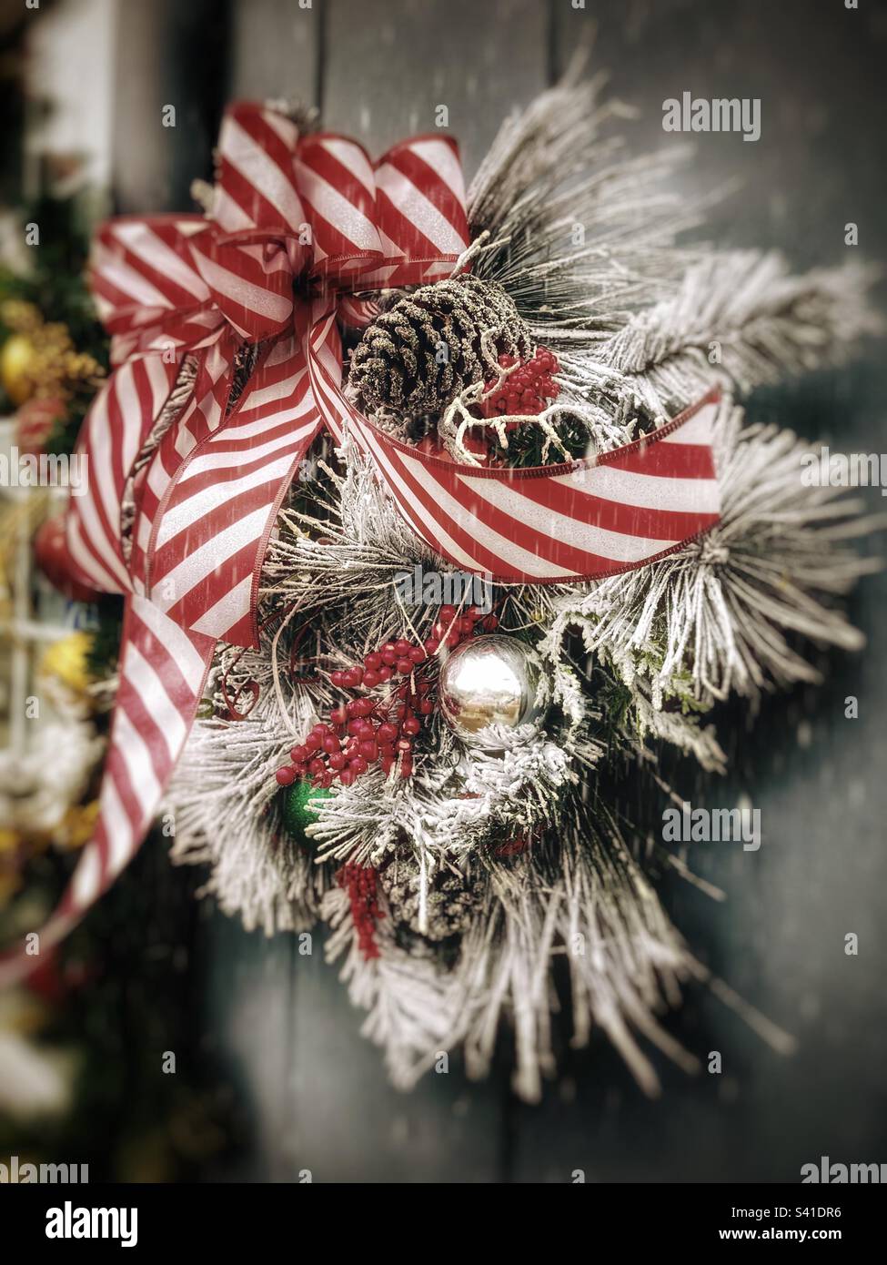 Couronne de Noël festive avec arc rouge et blanc accroché à une porte Banque D'Images