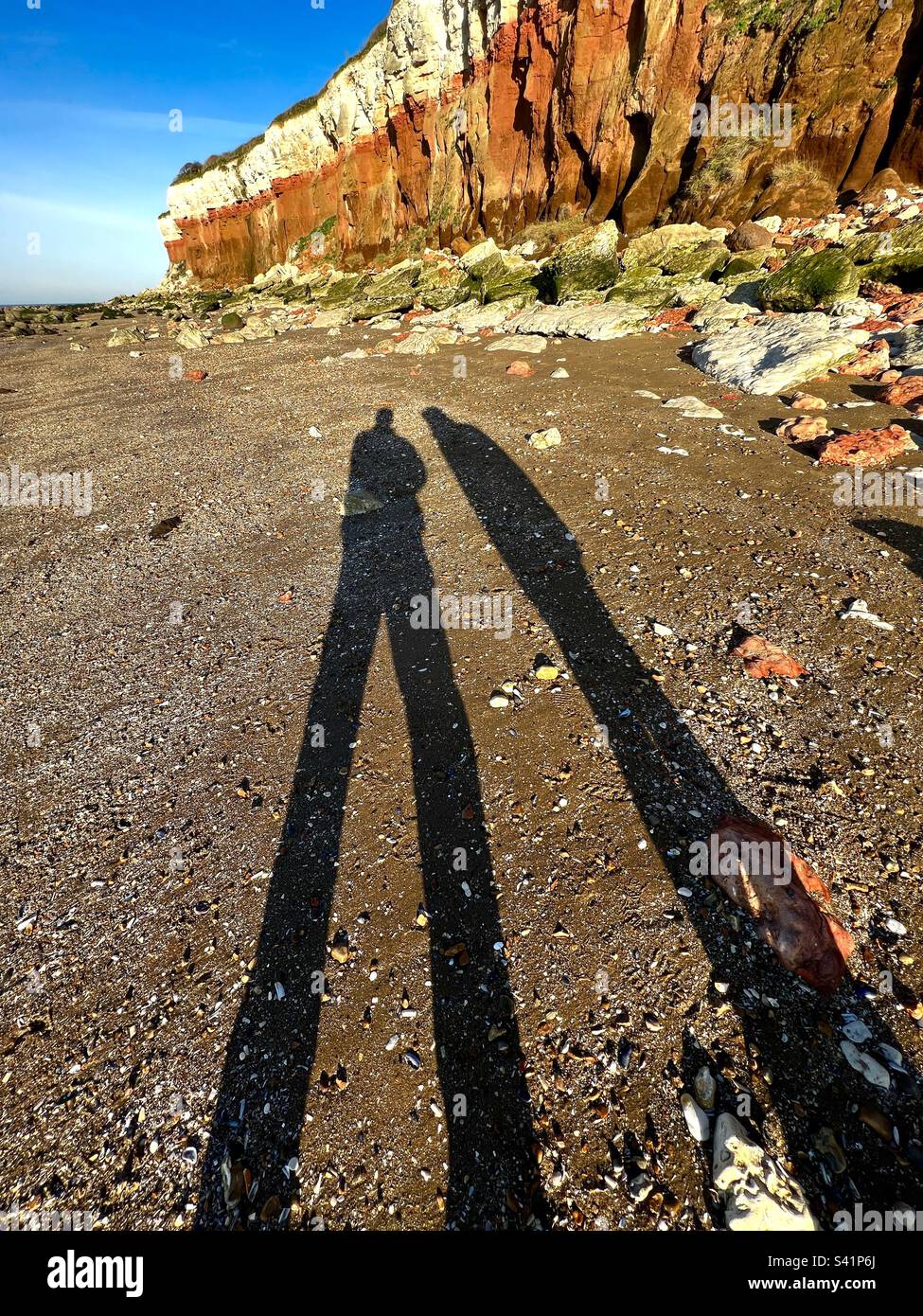 Ombres sur la plage sous la pierre calcaire rouge stratifiée et falaises de craie blanche à Hunstanton, Norfolk - Image de stock capturée avec un smartphone