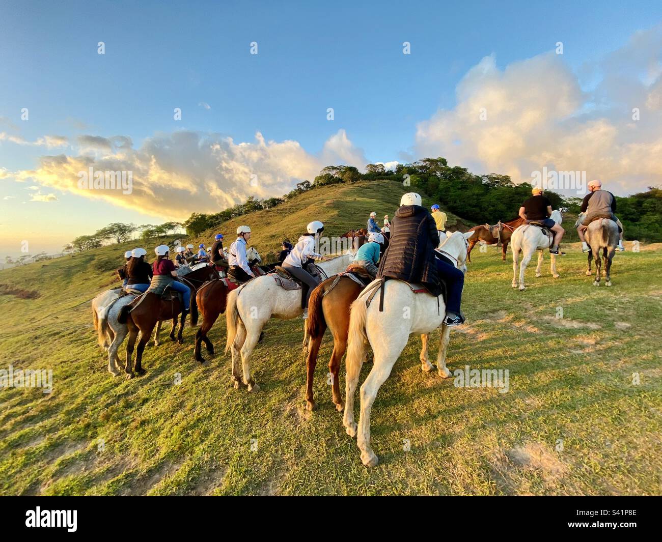 Un groupe de touristes à cheval pose pour des photos sur une colline au coucher du soleil au Costa Rica Banque D'Images