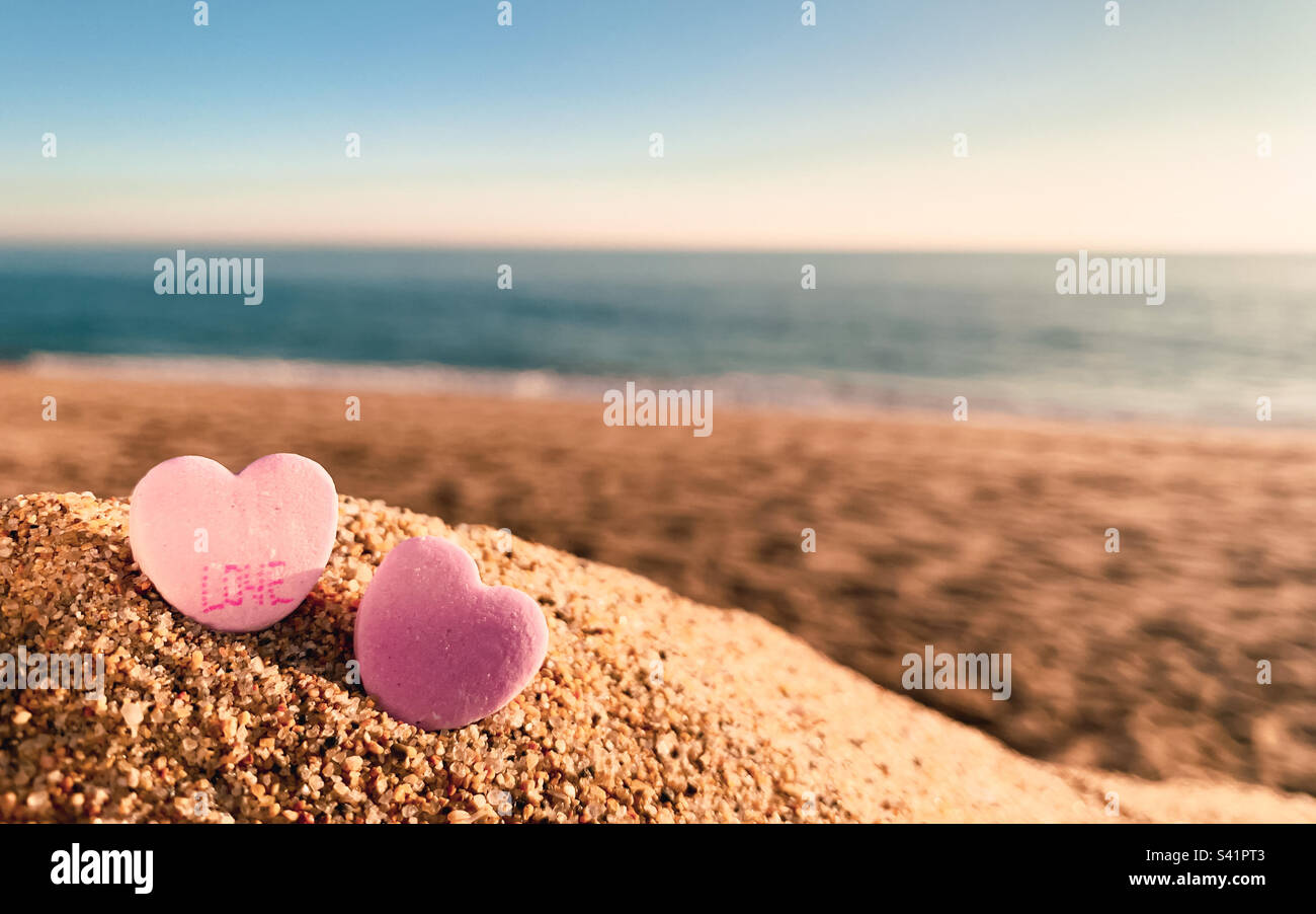 Vue à angle bas de deux cœurs de bonbons roses sur la plage. Concept plage mariage, amour, lune de miel - Image de stock capturée avec un smartphone