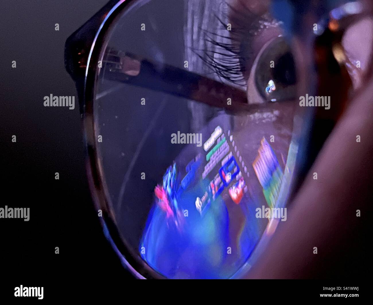 Les lumières et les écrans colorés se reflètent dans la vue macro des lunettes de femme, avec une attention particulière sur son œil la nuit Banque D'Images