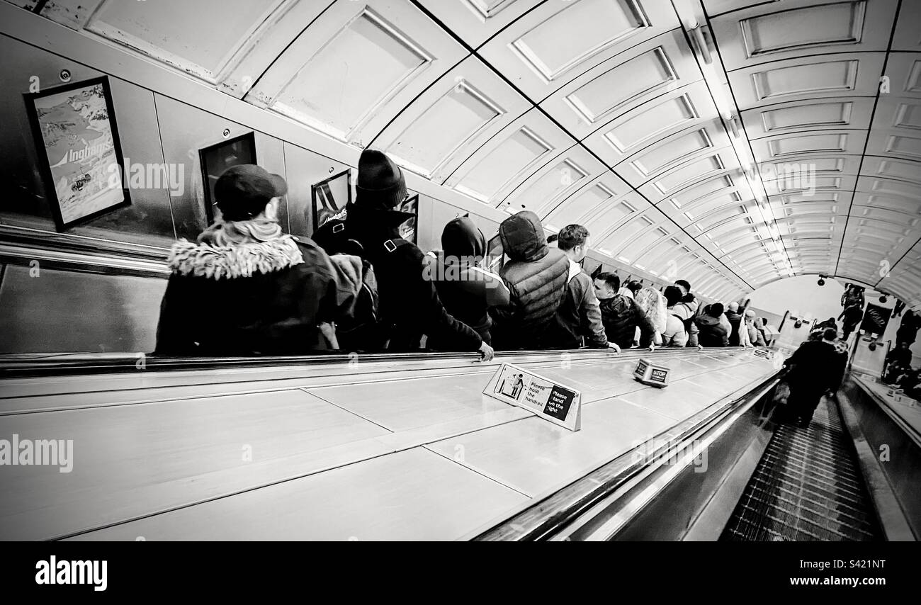 Les personnes qui descendent l'escalier roulant dans une station de métro de Londres au Royaume-Uni Banque D'Images