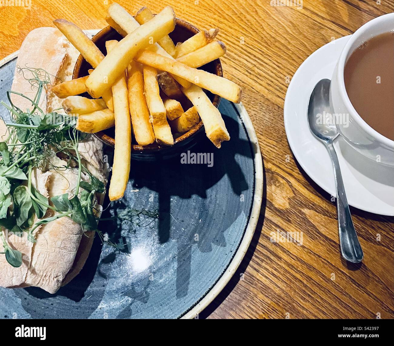 Pub Lunch in England - sandwich à la main de poisson avec pousses de pois et frites. Tasse de thé. Banque D'Images