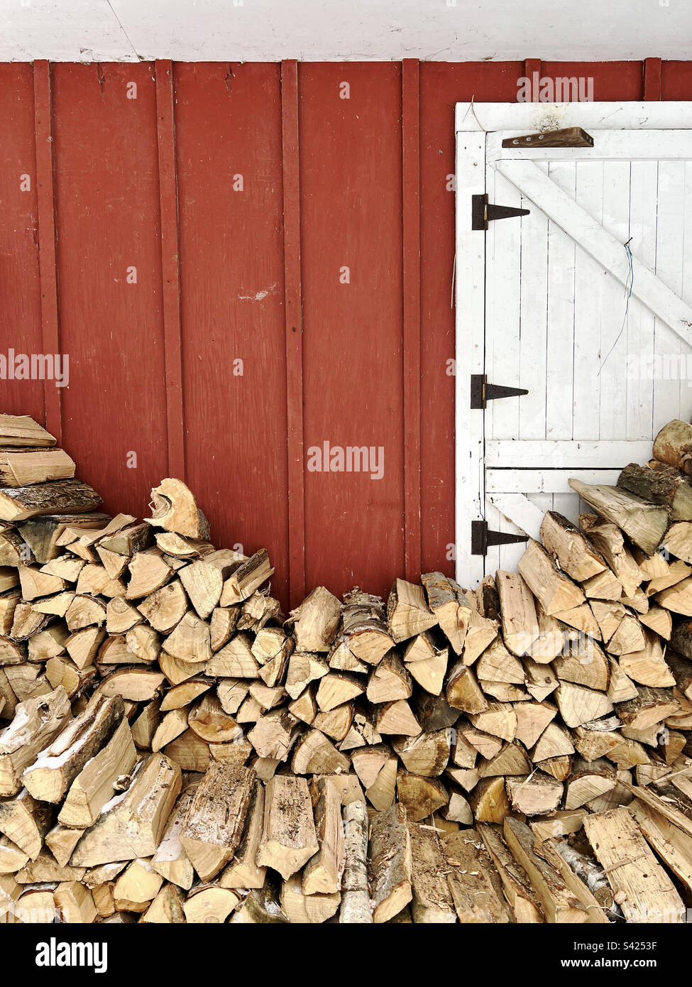 Une pile de billes contre une grange rouge dans le Vermont, aux États-Unis. Banque D'Images