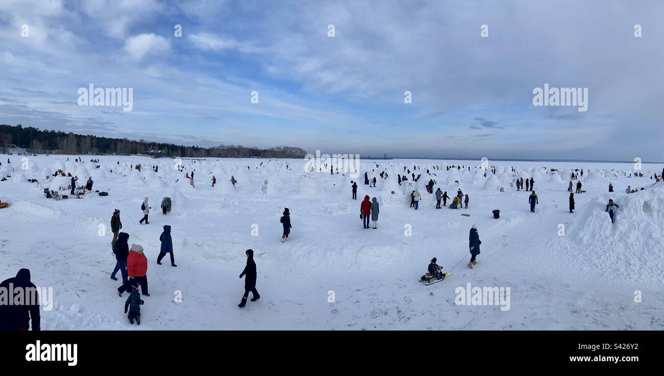 Beaucoup de personnes avec des familles et des enfants marchent sur la glace de la mer parmi un grand nombre de maisons faites de neige igloo. - Image de stock capturée avec un smartphone