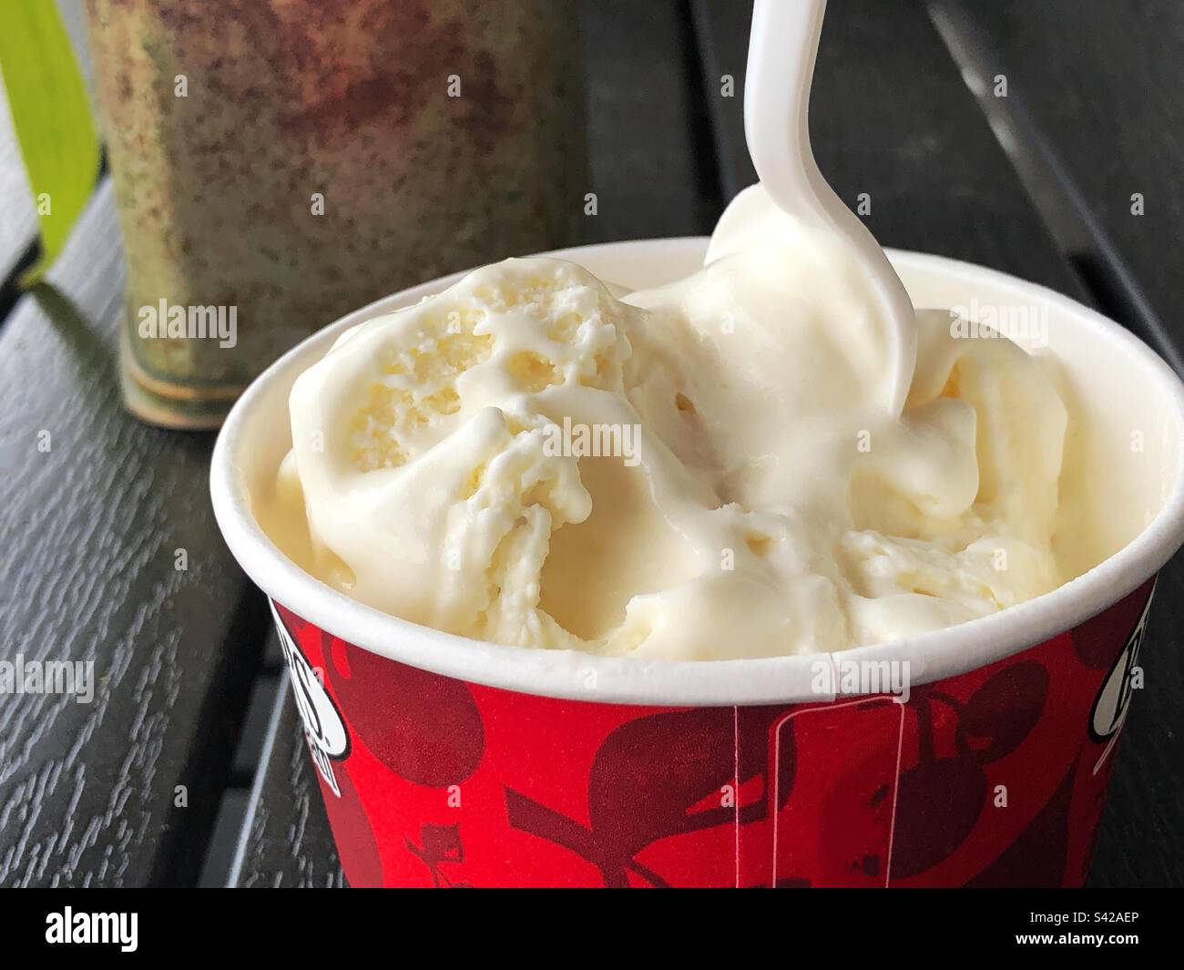Glace à la vanille dans un bac à papier avec une cuillère en plastique Banque D'Images