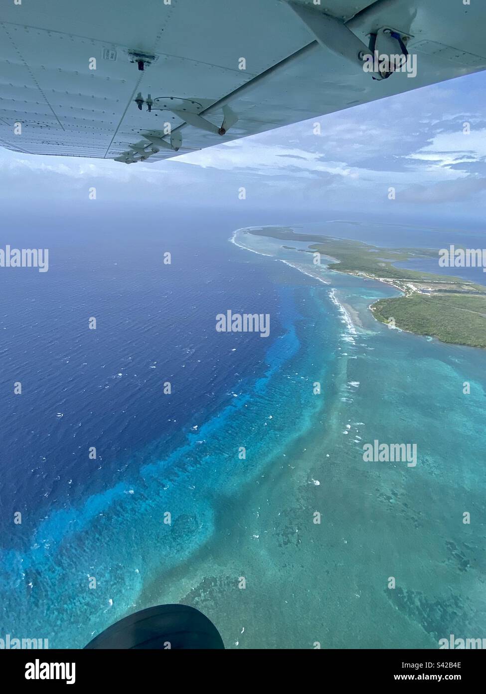 Vue aérienne à travers la fenêtre d'un petit avion au-dessus de l'eau bleue de l'atoll de Turneffe et de l'île de Turneff dans le système de barrière de corail du Belize Banque D'Images