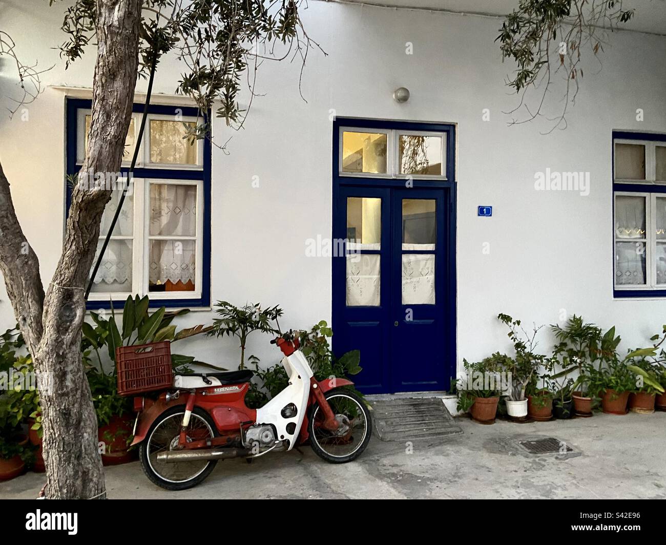 Porte bleue contre maison blanchie à la chaux avec mobylette à l'extérieur, Paros, Grèce Banque D'Images