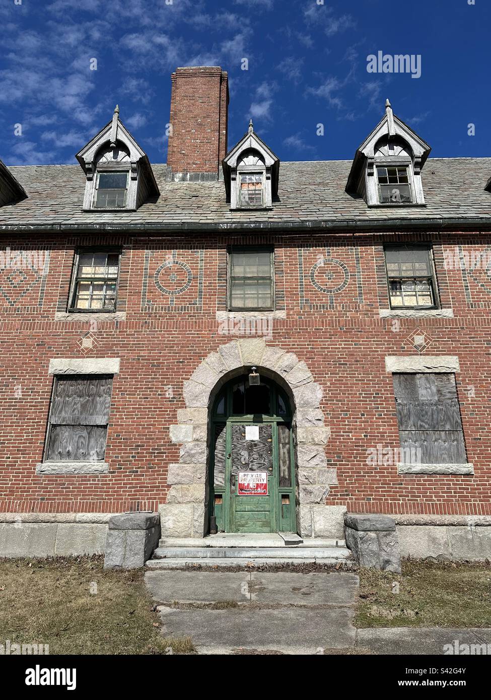 Bâtiment abandonné en brique rouge avec porte verte avec panneau indiquant propriété privée, pas d'intrusion. Au parc régional Seaside de à Waterford, Connecticut, États-Unis. C'était un ancien établissement médical. - Image de stock capturée avec un smartphone